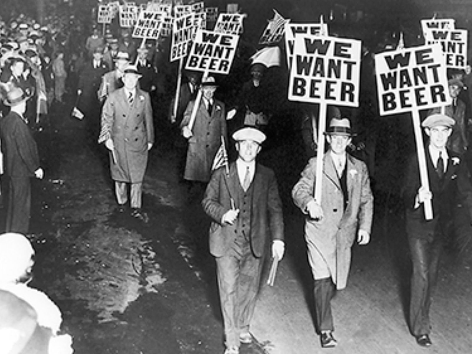 Manifestantes protestam contra a Lei Seca nos Estados Unidos, exibindo cartazes com a frase "We Want Beer" (Queremos Cerveja). Esta imagem ilustra o descontentamento popular com a proibição do álcool, um período que Al Capone soube explorar para construir seu império criminoso. Fonte: Library of Congress Prints and Photographs Division Washington, D.C.