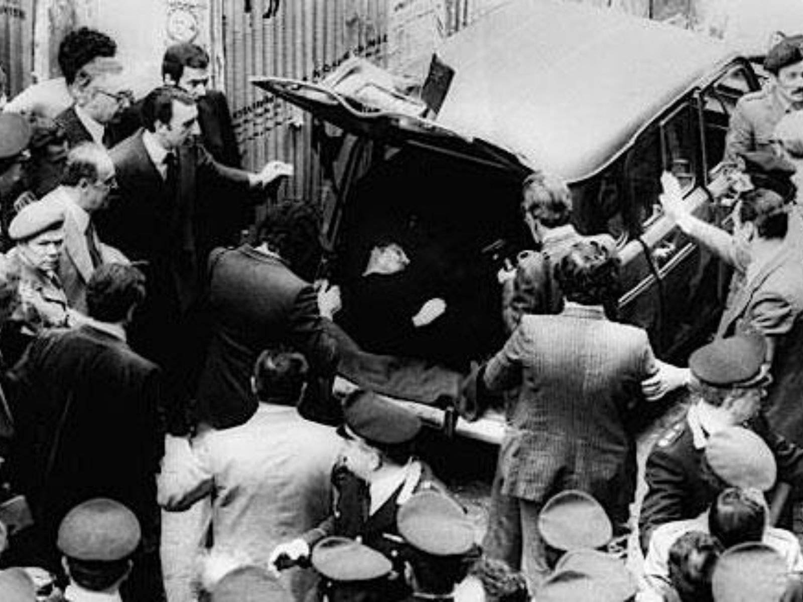 9 de maio de 1978, Via Caetani, Roma. Após 55 dias de cativeiro, o corpo de Aldo Moro foi encontrado no porta-malas de um Renault 4 vermelho, estacionado em uma rua simbolicamente localizada entre a sede da Democracia Cristã (Piazza del Gesù) e a do Partido Comunista Italiano (Via delle Botteghe Oscure). A escolha do local foi a última e mais cínica mensagem das Brigadas Vermelhas: para eles, ambos os partidos eram responsáveis pela morte de Moro. O corpo havia sido coberto com um cobertor; Moro estava vestido com o mesmo terno que usava no dia do sequestro, agora manchado de sangue. Ele havia sido morto com 11 tiros no peito, disparados com a mesma arma usada para matar seus seguranças 55 dias antes.