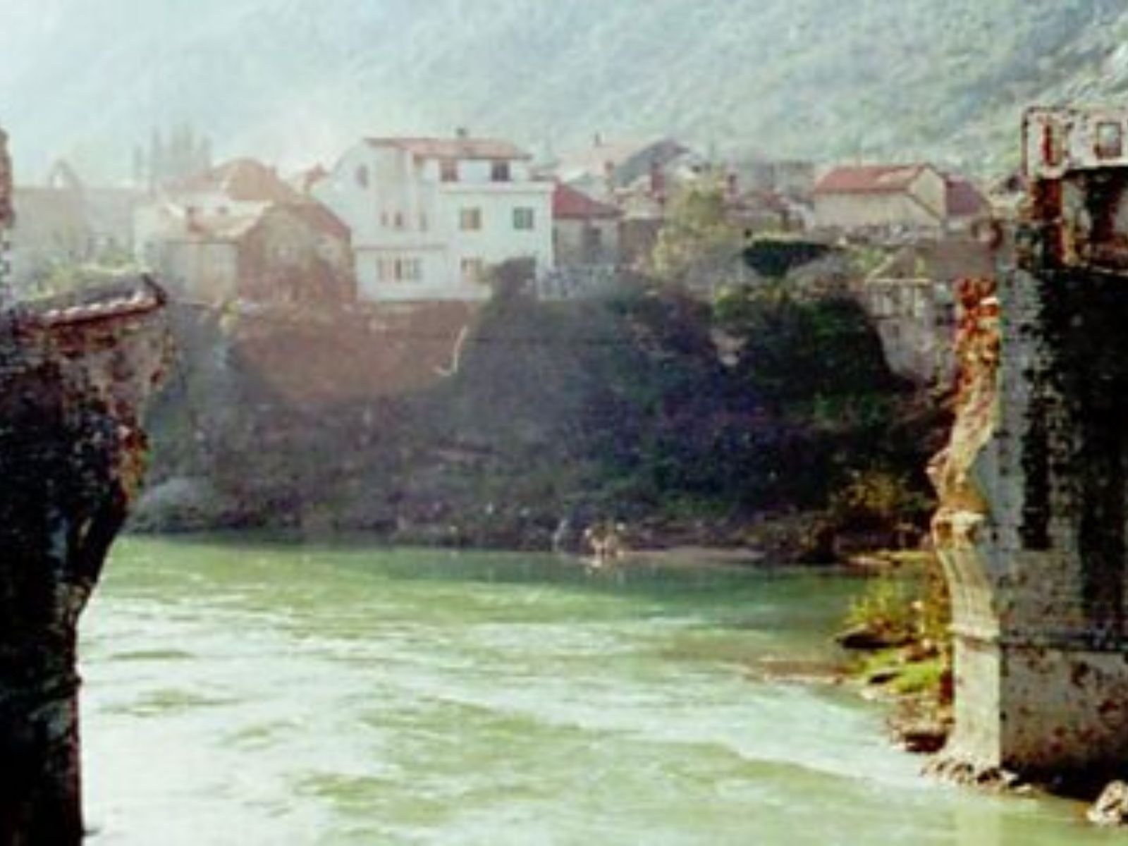 O momento exato em que a Ponte Velha (Stari Most) de Mostar, uma obra-prima da arquitetura otomana de 427 anos, desaba no rio Neretva após bombardeio sistemático por forças croatas (HVO).