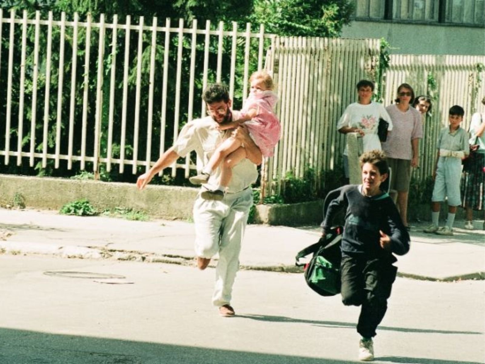 Um pai corre desesperadamente carregando sua filha pequena nos braços durante um ataque em Sarajevo.