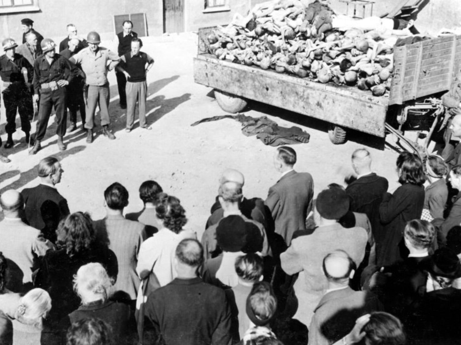 Civis alemães são obrigados a observar um caminhão carregado com os corpos de prisioneiros mortos de fome no campo de concentração de Buchenwald, em abril de 1945. A exposição forçada aos horrores dos campos foi uma tática para garantir que o povo alemão não pudesse negar o conhecimento dos crimes nazistas. Autor: U.S. Army Signal Corps / Harry S. Truman Presidential Library and Museum.