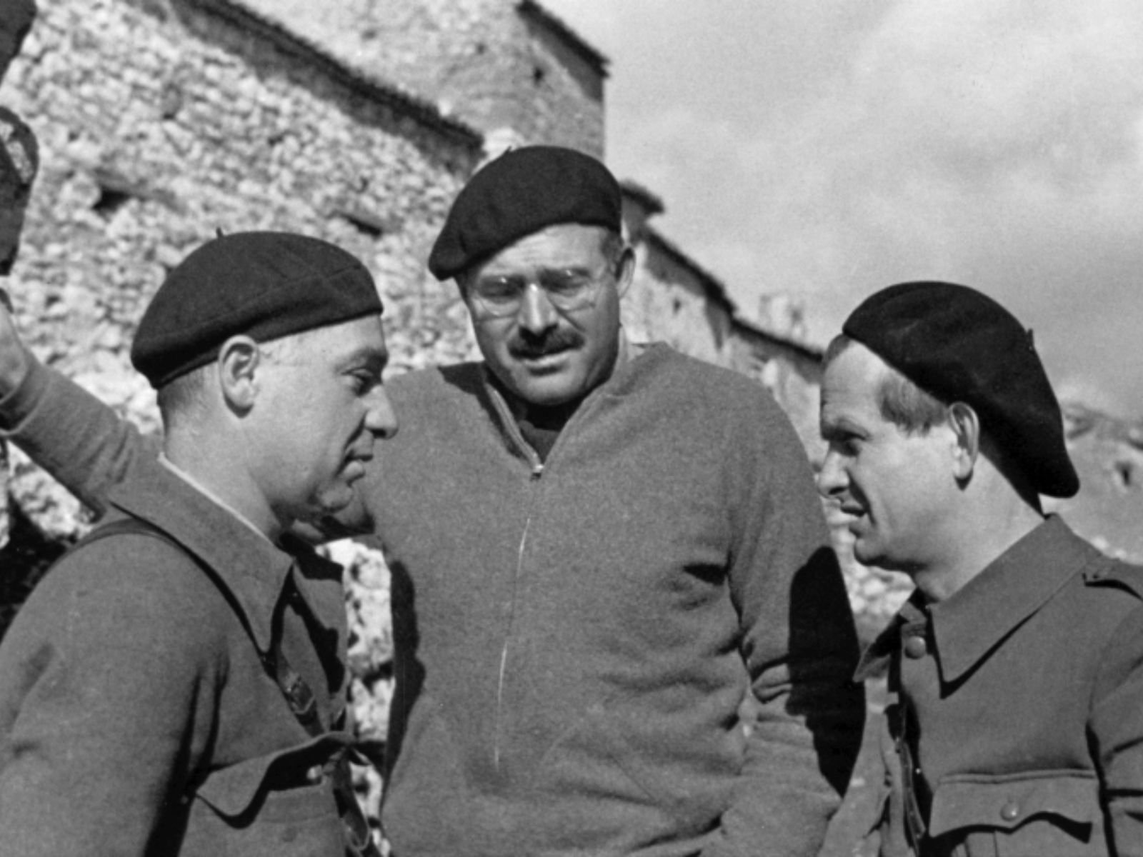 Ernest Hemingway com Ilya Ehrenburg (escritor e jornalista soviético, à esquerda) e Gustav Regler (escritor alemão e comissário político das Brigadas Internacionais, à direita) durante a Guerra Civil Espanhola, circa 1937. Hemingway está no centro usando suéter e boina. Fonte: Hemingway Photograph Collection, John F. Kennedy Presidential Library and Museum, Boston.