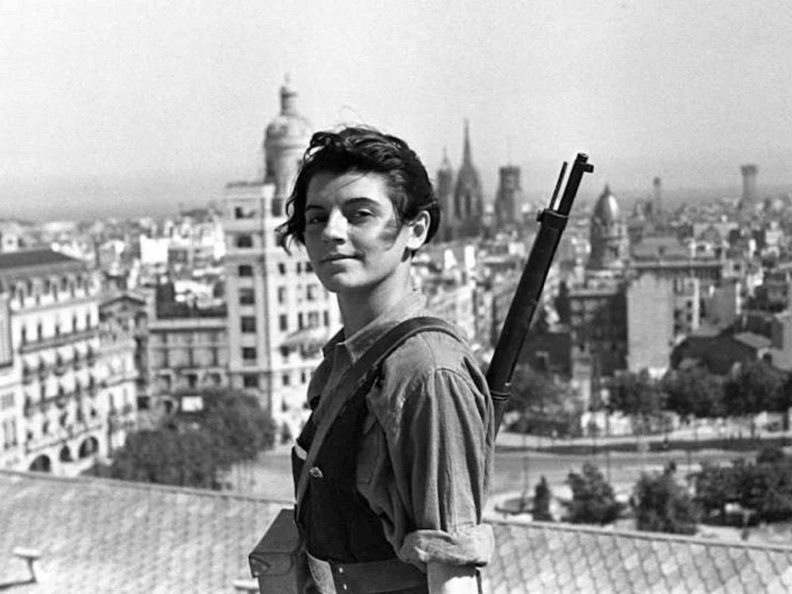 Marina Ginesta, à época com 17 anos, olha para a câmera com um rifle pendurado no ombro sobre o telhado do hotel Colón, em Barcelona, no dia 21 de julho de 1936.