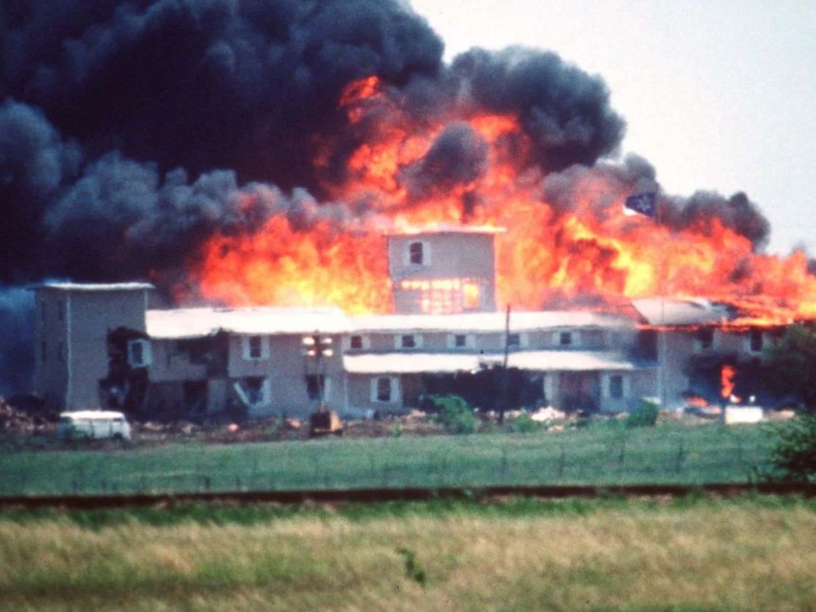 O complexo dos Ramo Davidianos em Waco, Texas, consumido pelas chamas em 19 de abril de 1993, após 51 dias de cerco pelo FBI. O incêndio que matou 76 pessoas, incluindo David Koresh e mais de 20 crianças, foi presenciado por Timothy McVeigh como observador. Este evento o horrorizou e o motivou a escolher exatamente a mesma data para seu ataque de vingança dois anos depois. Fonte: ABC News.