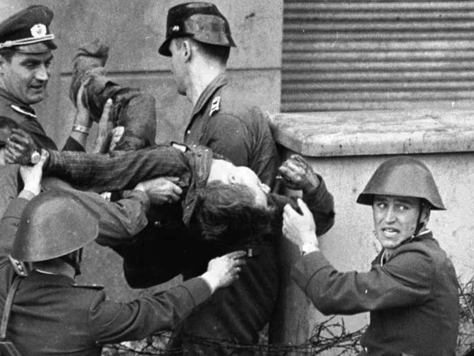 17 de agosto de 1962, 14h15. Peter Fechter, um pedreiro de 18 anos de Berlim Oriental, jaz sangrando na "faixa da morte" após ser baleado por guardas da fronteira enquanto tentava escalar o Muro. Fechter e seu amigo Helmut Kulbeik haviam planejado a fuga cuidadosamente. Eles correram juntos em direção ao Muro perto do Checkpoint Charlie. Kulbeik conseguiu escalar e pular para o lado ocidental. Fechter estava quase no topo quando guardas da Alemanha Oriental abriram fogo. Ele foi atingido na pelve e caiu de volta para a faixa da morte. Por quase uma hora, Fechter gritou por ajuda enquanto sangrava. Soldados americanos e berlinenses ocidentais não podiam ajudá-lo sem provocar um incidente internacional. Guardas da Alemanha Oriental não o socorreram. Ele morreu antes de ser removido. Sua morte foi testemunhada por centenas de pessoas e fotografada, tornando-se um símbolo da brutalidade do regime. Peter Fechter foi a 27ª pessoa a morrer tentando cruzar o Muro de Berlim.