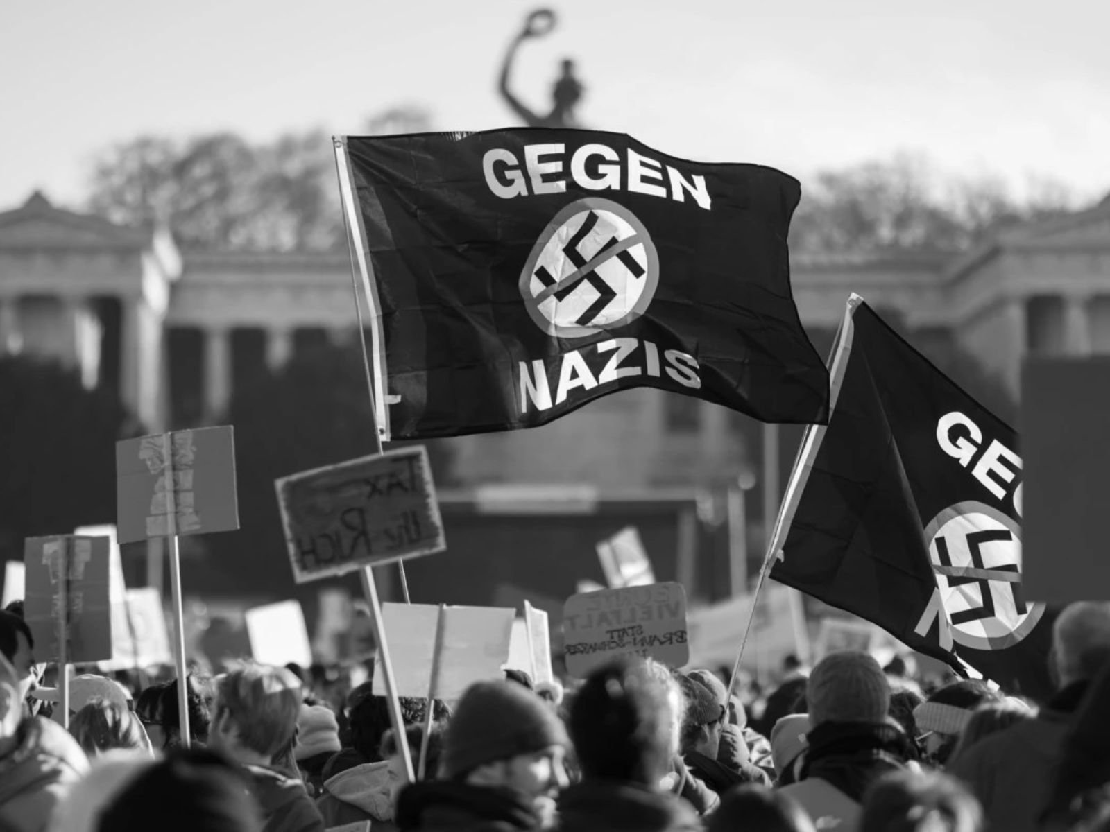 Manifestantes de extrema-direita com bandeiras contendo suásticas durante um protesto na Alemanha. A imagem ilustra a persistência de grupos neonazistas no país décadas após o fim da Segunda Guerra Mundial, um desafio contínuo para a sociedade alemã.