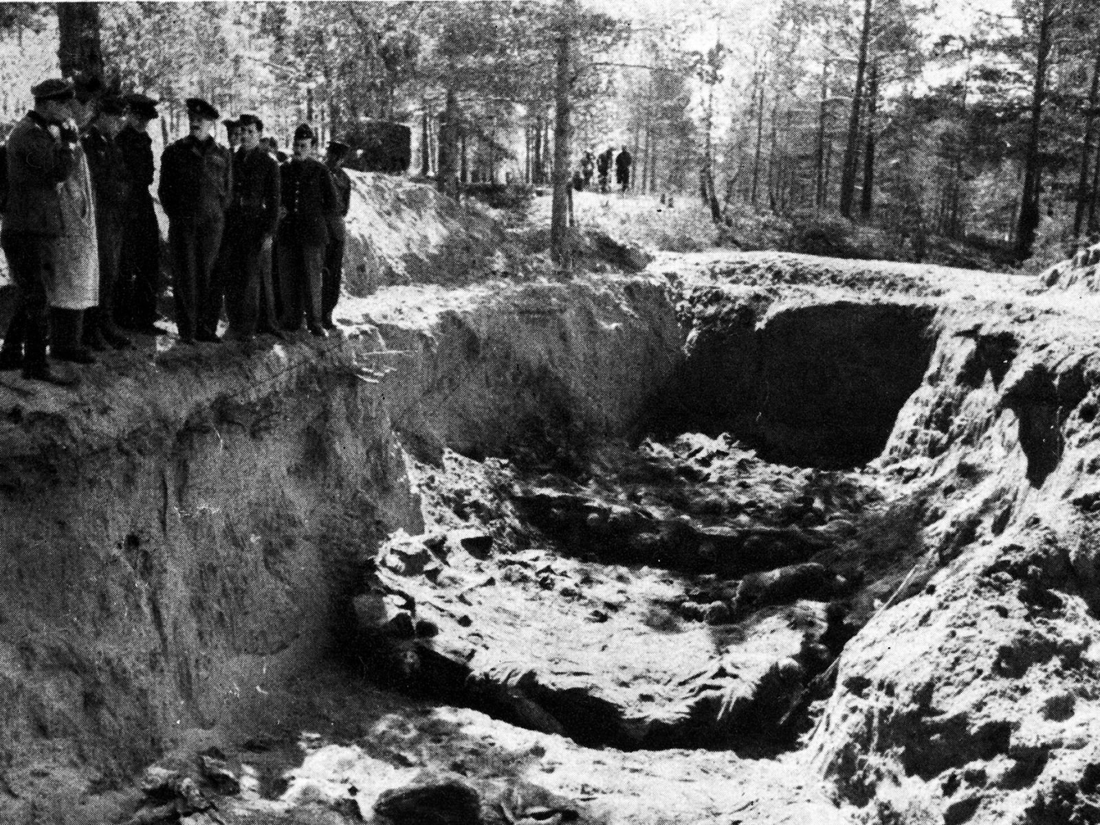 Fotografia mostrando uma das valas comuns descobertas na Floresta de Katyn, com pessoas observando ao redor. Fonte: Warsaw Institute
