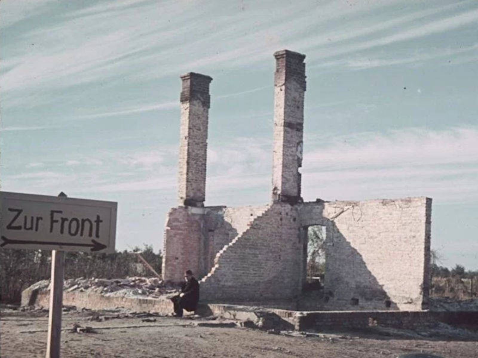Ruínas perto da cidade de Varsóvia em 1939. A placa indica a direção da frente de batalha. Foto: Hugo Jaeger.